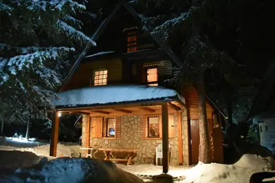 a log cabin in the snow at night at Apartman Sani in Vlasic