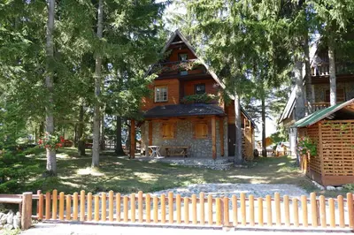 a wooden house with a fence in front of it at Apartman Sani in Vlasic