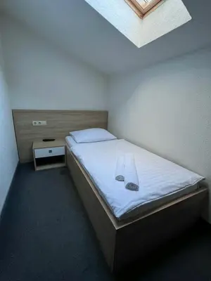 a bedroom with a bed with a white sheets and a window at Motel Papić in Tomislavgrad