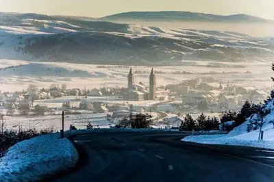 a road leading to a city in the snow at Hotel Kupres in Kupres