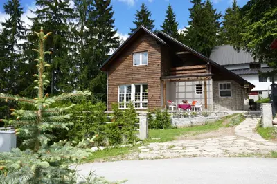 a log home with a woman sitting on the porch at Vlašić House in Vlasic