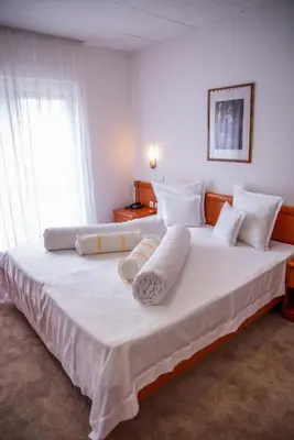 a bedroom with a large white bed with white pillows at Hotel Integra in Doboj