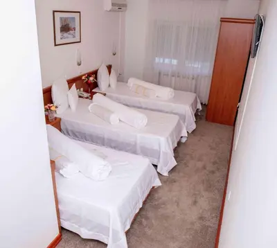 a row of beds in a room with a mirror at Hotel Integra in Doboj