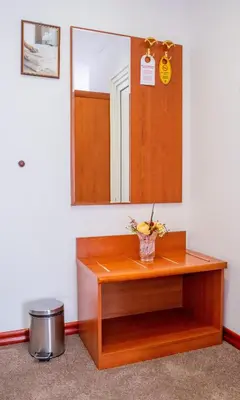 a dressing table with a mirror and a vase of flowers on it at Hotel Integra in Doboj