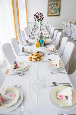 a long table with white chairs and plates of food at Hotel Integra in Doboj
