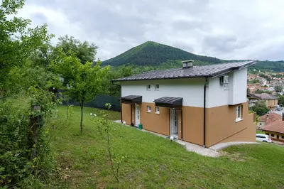 a house on a hill with a mountain in the background at Piramida Visoko in Visoko