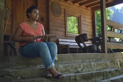 a woman sitting on some steps playing a guitar at Holiday Park Zelenkovac in Podrašnica
