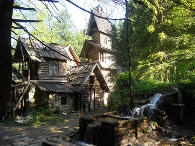 an old house with a waterfall in front of it at Holiday Park Zelenkovac in Podrašnica