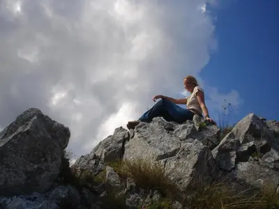 a woman sitting on top of a rocky mountain at Holiday Park Zelenkovac in Podrašnica