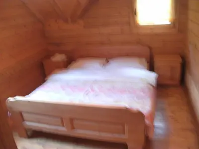 a bed in a wooden cabin with a window at Holiday Park Zelenkovac in Podrašnica