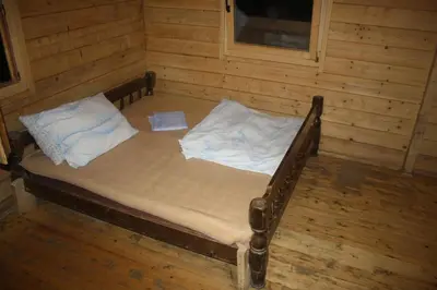 a small bed in a room with wooden walls at Holiday Park Zelenkovac in Podrašnica