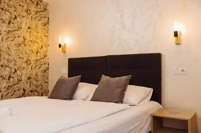 a bedroom with a large bed with a black headboard at Guest House Babilon in Prijedor