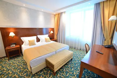 a hotel room with a bed and a desk at Hotel Mellain in Tuzla