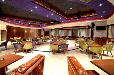 a restaurant with tables and chairs and purple ceilings at Hotel Mellain in Tuzla