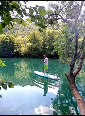 a boy is standing on a paddle board in the water at Home-Vasva and Hazim in Ćukovi