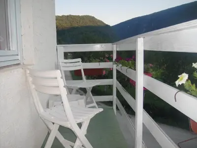 two white chairs sitting on a balcony with flowers at Home-Vasva and Hazim in Ćukovi