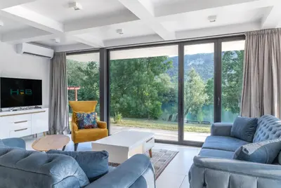 a living room with blue furniture and a large window at Villa Una Residence in Bihać