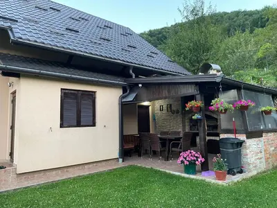 a house with a patio with a table and flowers at Holiday Home Ajaz Bihac in Bihać