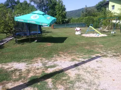 a playground with a blue umbrella and a swing at Ribarska Vila in Donje Lohovo