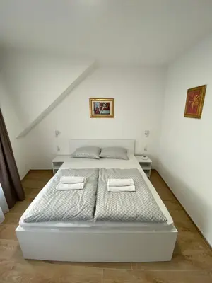 a white bed in a white room with two towels at Prenoćište Stari Grad - Old Town in Tuzla