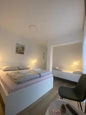 a bedroom with two beds and a chair at Prenoćište Stari Grad - Old Town in Tuzla