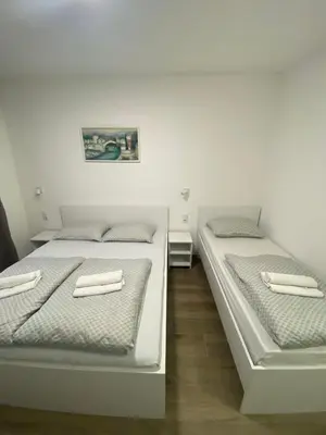 two beds in a room with white walls at Prenoćište Stari Grad - Old Town in Tuzla