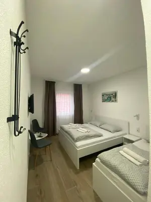 a bedroom with two beds and a table and a chair at Prenoćište Stari Grad - Old Town in Tuzla