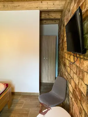 a room with a chair and a tv on a brick wall at Holiday park Hajducka cesma in Dubovsko