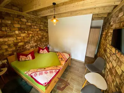 a bedroom with a green bed in a brick wall at Holiday park Hajducka cesma in Dubovsko