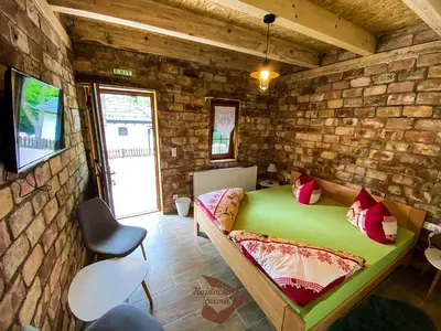 a bedroom with a green bed in a brick wall at Holiday park Hajducka cesma in Dubovsko