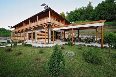 a large wooden house with a pavilion in a yard at Zlatna Nit Pansion in Bosanska Krupa