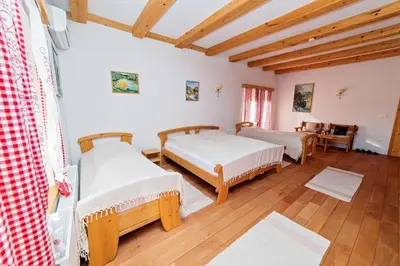 two beds in a room with wooden floors and wooden ceilings at Zlatna Nit Pansion in Bosanska Krupa