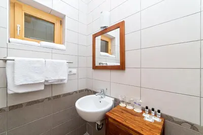 a white bathroom with a sink and a mirror at Zlatna Nit Pansion in Bosanska Krupa
