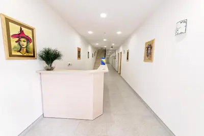 a hallway with white walls and a hallway with paintings at Zlatna Nit Pansion in Bosanska Krupa