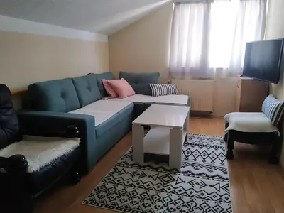 a living room with a blue couch and a table at Apartment Edin in Bihać