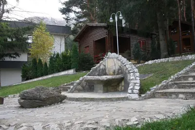 a stone fireplace in a yard with a building at Hotel Balkana Vidović in Mrkonjić Grad