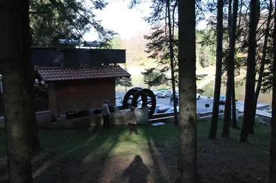 a group of people standing in a park with a waterwheel at Hotel Balkana Vidović in Mrkonjić Grad