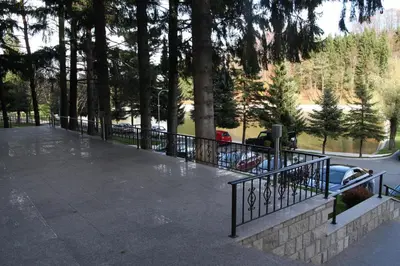 a park with a fence and a parking lot with cars at Hotel Balkana Vidović in Mrkonjić Grad