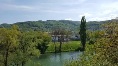 a river with trees and a house in the background at Apartmani Kastel in Banja Luka