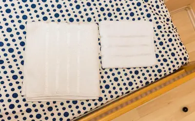 a bed with polka dot wallpaper and two towels at Apartmani Kastel in Banja Luka