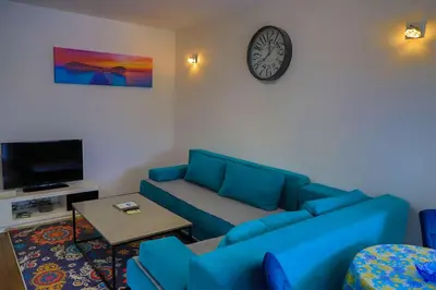 a living room with a blue couch and a clock at Holiday Homes Pozitiva in Bihać