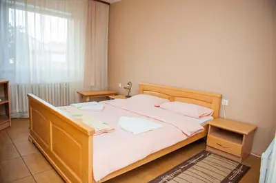 a bedroom with a large bed with white sheets and a window at Prenoćište 