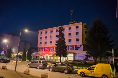 a pink building with cars parked in a parking lot at Prenoćište 