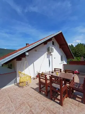 a patio with a table and chairs and a building at Apartman Denis Una in Lužine