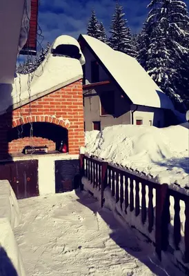 a snow covered house with a brick oven at Vikend Kuća Iman in Vlasic