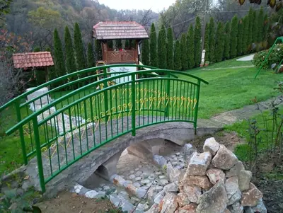 a green bridge over a stream in a garden at Holiday Home Pharaoh in Visoko