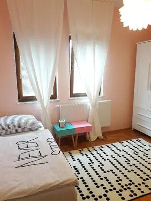 a bedroom with a bed and a table and windows at Farah Superior Apartments in Bihać