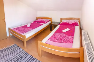 two beds in a room with pink sheets at Apartments Aqua Resa in Bihać