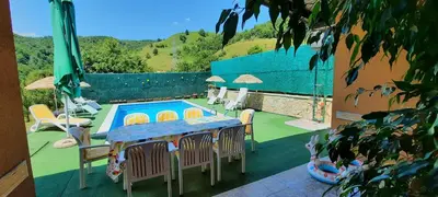 a patio with a table and chairs and a swimming pool at Villa Meli in Visoko