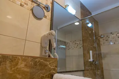 a bathroom with a shower with a blow dryer on the wall at Hotel Rekic in Bihać